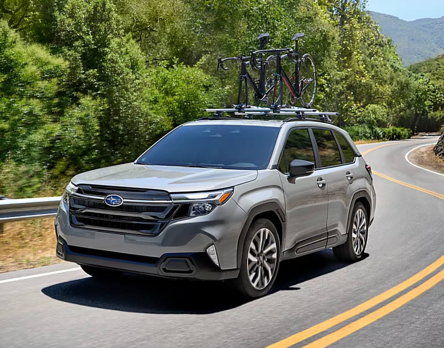 Subaru Forester Touring with roof rack driving on winding mountain road.
