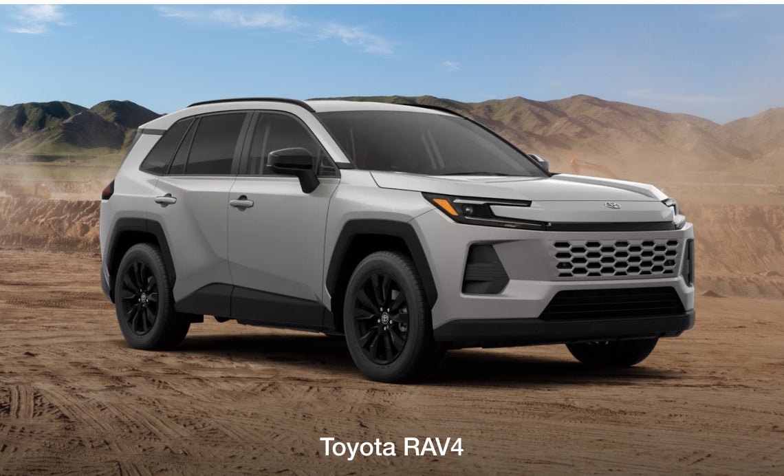 A 2026 Toyota RAV4 Hybrid is parked on a sandy terrain with distant mountains under a clear blue sky, conveying a rugged and adventurous tone.